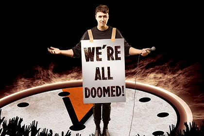 Daniel Howell on stage with a sign that says "We're All Doomed"